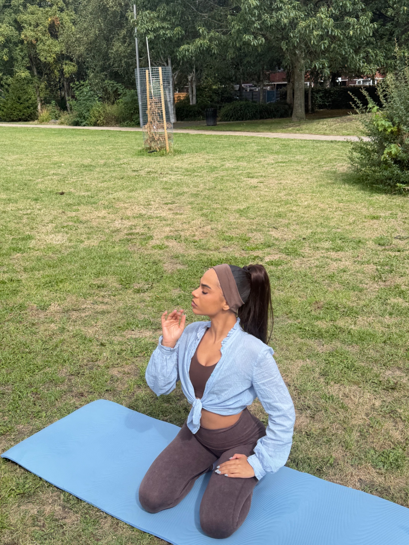 Ana breathing calmly kneeling on a yoga mat in the park